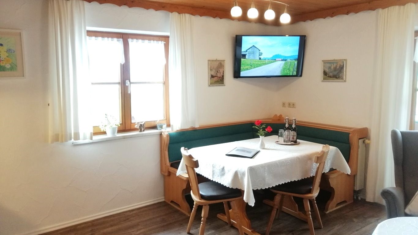 Der Esstisch mit gemütlicher Eckbank und der Sat-TV in der Ferienwohnung Nebelhorn