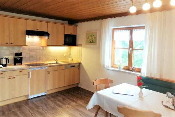 Großer Esstisch mit Eckbank und Küchenzeile in der Ferienwohnung Nebelhorn im Haus Alpenblick